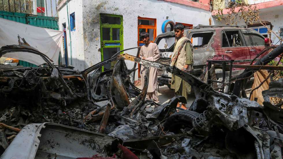 epa09476246 Family members of the victims of a US drone strike, stand beside the wreckage of the damaged vehicles, at their home, a day after US apologised for mistakenly attacking the civilians, in Kabul, Afghanistan, 19 September 2021. A US drone strike at a civilian compound on 29 August killed at least 10 persons including seven children in Kabul.  EPA/STRINGER