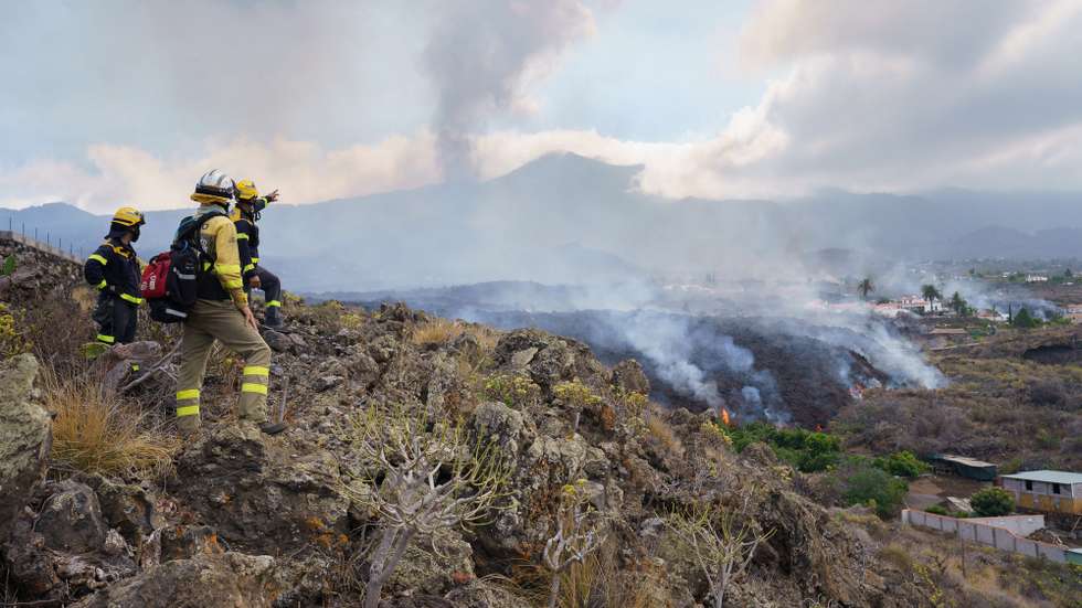 epa09479206 Firemen look at the lava flow from the Cumbre Vieja volcano as it moves towards the neighborhood of Todoque, in the municipality of Los Llanos de Aridane, after all locals were evacuated, in La Palma, Canary Islands, Spain, 21 September 2021.The Cumbre Vieja volcano began to erupt in Montana Rajada in the municipality of El Paso on 19 September.  EPA/Ramon de la Rocha