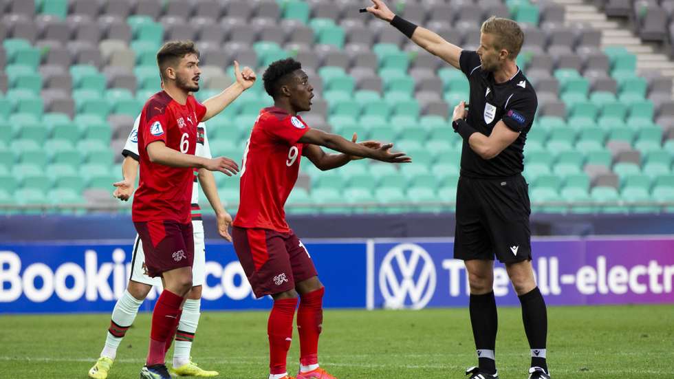 epa09108995 Swiss players Felix Mambimbi (C) and Toni Domgjoni (L) argue with Swedish referee Glenn Nyberg (R) during the UEFA European Under-21 Championship group D soccer match between Switzerland and Portugal in Ljubljana, Slovenia, 31 March 2021.  EPA/PETER KLAUNZER