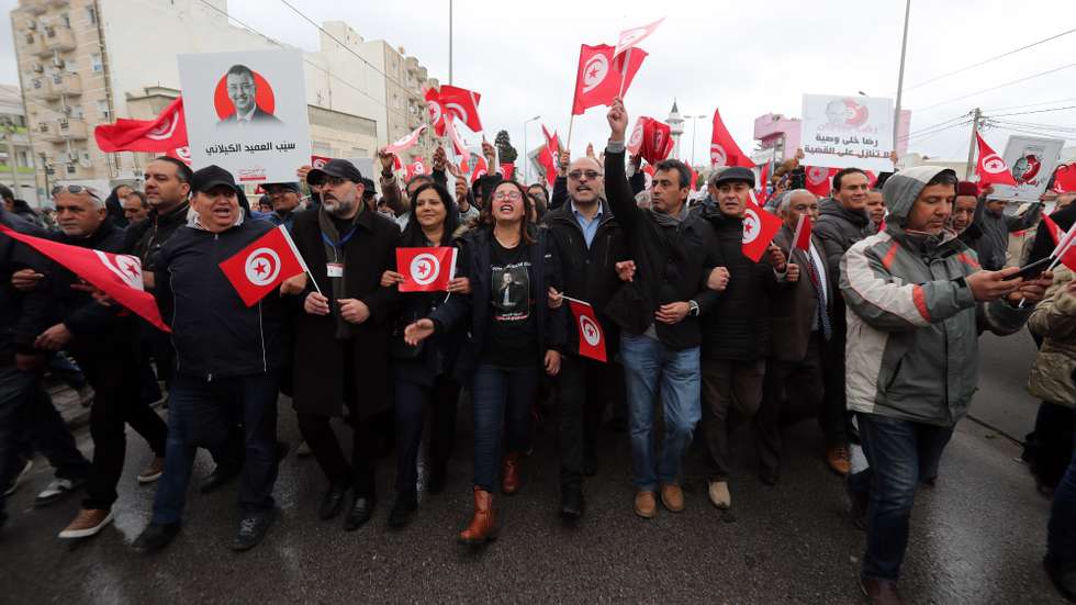 epa09837748 Demonstrators hold Tunisian national flags during a protest against Tunisian President Kais Saied's seizure of governing powers, during the 66th anniversary of Tunisia's independence in Tunis, Tunisia, 20 March 2022. France ended  its protectorate over Tunisia on 20 March 1956.  EPA/MOHAMED MESSARA