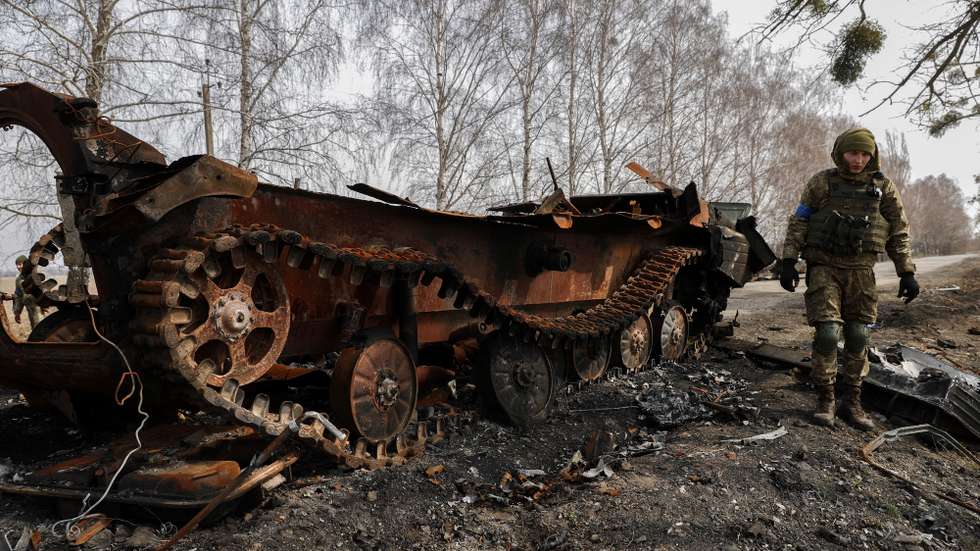epa09862359 Ukrainian servicemen inspect the remains of a Russian tank that was damaged in the fighting between Ukrainian and Russian forces on a road leading to the Ukrainian city of Makariv, west of Kyiv, Ukraine, 31 March 2022. On 24 February Russian troops had entered Ukrainian territory in what the Russian president declared a 'special military operation', resulting in fighting and destruction in the country, a huge flow of refugees, and multiple sanctions against Russia.  EPA/ATEF SAFADI