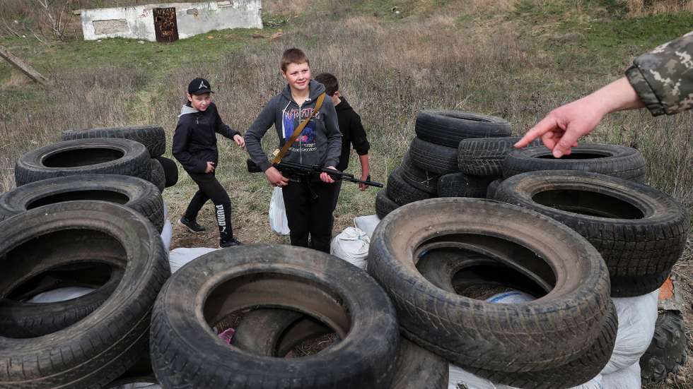 An unidentified territorial defence member talks to Ivan, 14 years (R), who borrowed his unloaded kalasnikov, Maxin, 14 (R)  and Dennis, 13,  in a fake checkpoint they made in the neighborhood in Ovidiopol. They asks for a password and passports just for fun. In the future they want to be soldiers to defend the country, Odessa, 01 April 2022. On 24 February Russian troops had entered Ukrainian territory in what the Russian president declared a 'special military operation', resulting in fighting and destruction in the country, a huge flow of refugees, and multiple sanctions against Russia. NUNO VEIGA/LUSA