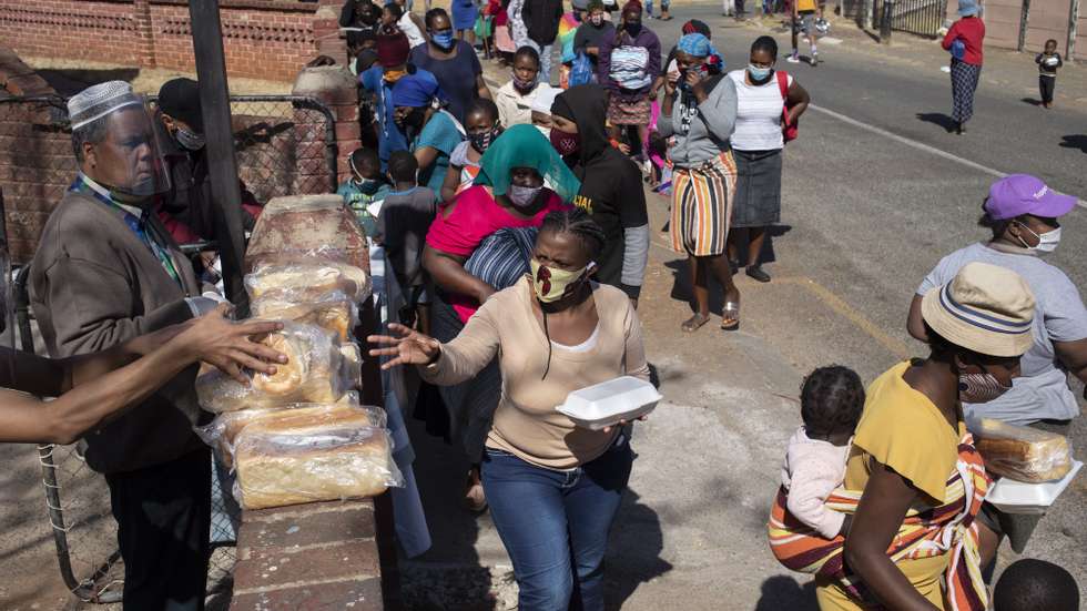 epa08578619 Women receive bread at a food handout during the Eid al Adha at the &#039;Hunger Has No Religion&#039; feeding scheme, in Johannesburg, South Africa, 01 August 2020. The local Muslim community spent the time they would have shared with family celebrating Eid al-Adha by feeding hundreds who are facing food insecurity due to the effects of the 5th month of pandemic lockdown. Food insecurity is one of the main issues facing the country since the start of coronavirus pandemic lockdown.  EPA/KIM LUDBROOK