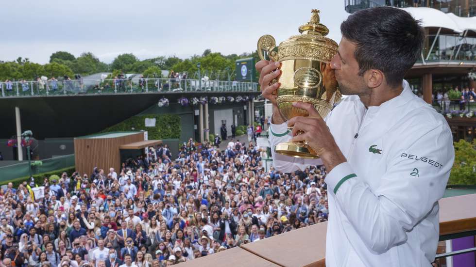 epa09338205 Spectators watching on as Novak Djokovic of Serbia poses with the Gentlemen's Singles Trophy on the balcony of the Clubhouse after winning the Gentlemen's Singles at The Wimbledon Championships tennis tournament in Wimbledon, Britain, 11 July 2021.  EPA/AELTC / Bob Martin / POOL   EDITORIAL USE ONLY