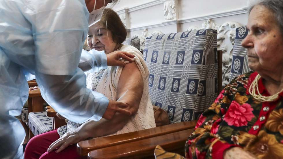 Uma utente de um lar de terceira idade é vacinada por uma enfermeira com a quinta dose da vacina contra a covid-19, em Lisboa, 19 de maio de 2022. TIAGO PETINGA/LUSA