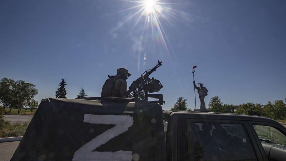 epa10009665 A picture taken during a visit to Mariupol organized by the Russian military shows a Russian serviceman in a vehicle with letter 'z' guards on the road in front of the monument of steel worker with Russian National flag at the entrance to the city of Mariupol, Donetsk region, Ukraine, 12 June 2022. On 24 February Russian troops entered Ukrainian territory starting a conflict that has provoked destruction and a humanitarian crisis. According to the UNHCR, more than six million refugees have fled Ukraine, and a further 7.7 million people have been displaced internally within Ukraine since.  EPA/SERGEI ILNITSKY