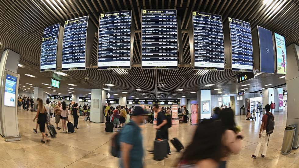 epa10091065 Passengers look at a departures screens at Adolfo Suarez Airport in Madrid, Spain, 25 July 2022, on first day of a planned four-day strike action to which Ryanair cabin crew are called for, this week.  EPA/FERNANDO VILLAR