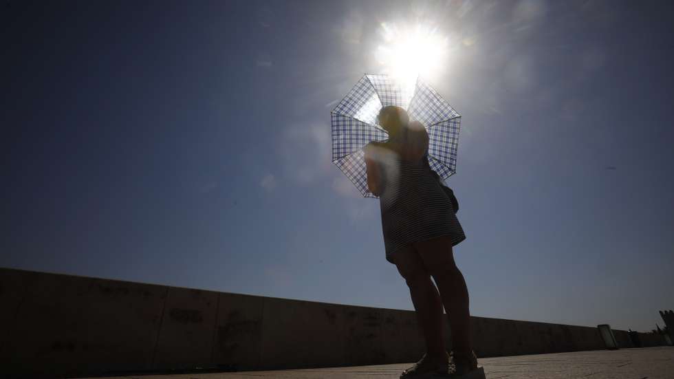 epa10101361 A woman protects herself from the sun with an umbrella as she walks across the Roman bridge in Cordoba, Spain, 01 August, 2022. The third heat wave of this summer has already begun in some areas of Andalusia and in some towns the temperatures exceeded 42 degrees on July 31.  EPA/SALAS