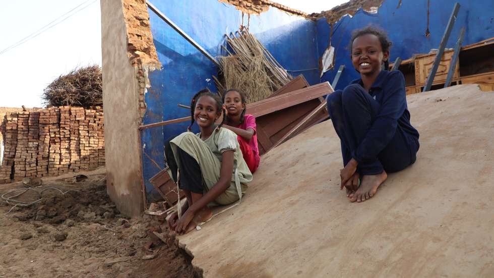 epa10135173 Sudanese children pose for photos as they sit on their destroyed house at a flooded area of Al Jazirah state, Sudan, 23 August 2022. According to the Sudanese Council for Civil Defense, at least 79 people died in incidents related to the recent floods in the country. Thousands of homes were damaged due to the floods that affected South Darfur, North Kordofan, and Al Jazirah state.  EPA/MOHND AWAD