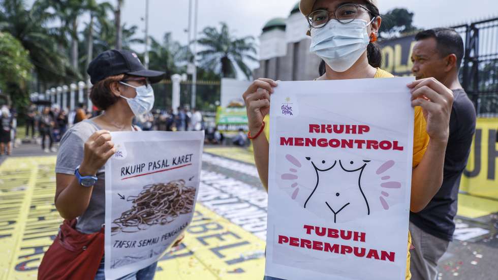 epa10349143 A protester holds a placard reading 'The criminal law controls women's body' during a protest against the draft of a new criminal law, outside the parliament building in Jakarta, Indonesia, 05 December 2022. The new criminal law that will punish sex before marriage with imprisonment, is expected to be passed by Indonesia's parliament this month.  EPA/MAST IRHAM