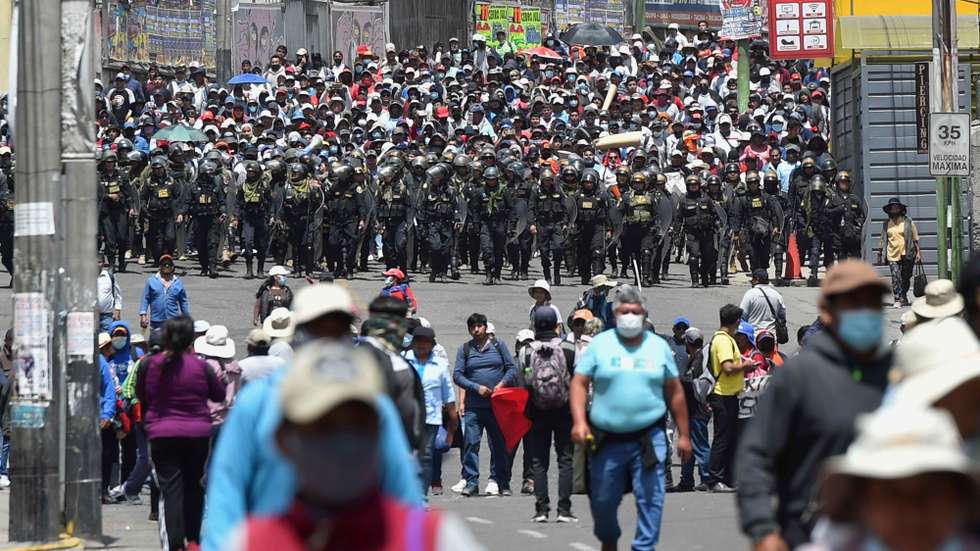 epa10365706 Police officers watch over a demonstration by supporters of deposed President Pedro Castillo, in Arequipa, Peru, 14 December 2022. The Peruvian Government declared on 14 December a state of emergency throughout the country for 30 days, which implies the suspension of assembly rights, inviolability of the home and freedom of transit, among others, while evaluating the possibility of declaring a curfew.  EPA/JOSE SOTOMAYOR