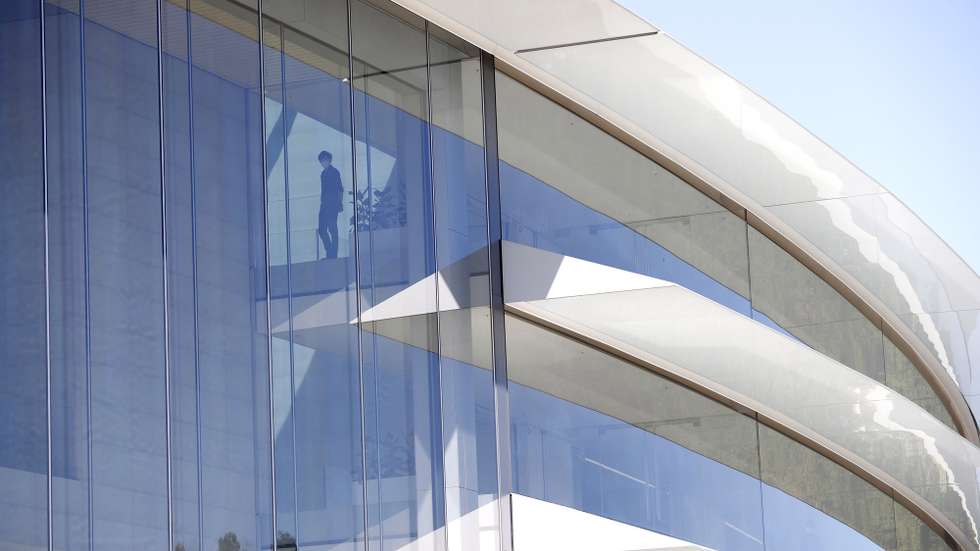 epa09999366 People watch from inside Apple headquarters as Apple CEO Tim Cook speaks during the 2022 Apple Worldwide Developers Conference (WWDC) on the campus of Apple Park in Cupertino, California, USA, 06 June 2022. The event is the first with limited media and developers in attendance since 2019.  EPA/JOHN G. MABANGLO