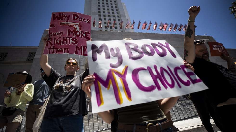 epa10034084 Demonstrators hold posters reading 'My body my choice' and 'Why does a gun have more rights than me?!' during an abortion rights protest following the decision by the US Supreme Court to overturn the Roe v. Wade ruling, in front of the City Hall in Los Angeles, California, USA, 25 June 2022. The Supreme Court decision opens the possibility for states to ban abortion.  EPA/ETIENNE LAURENT
