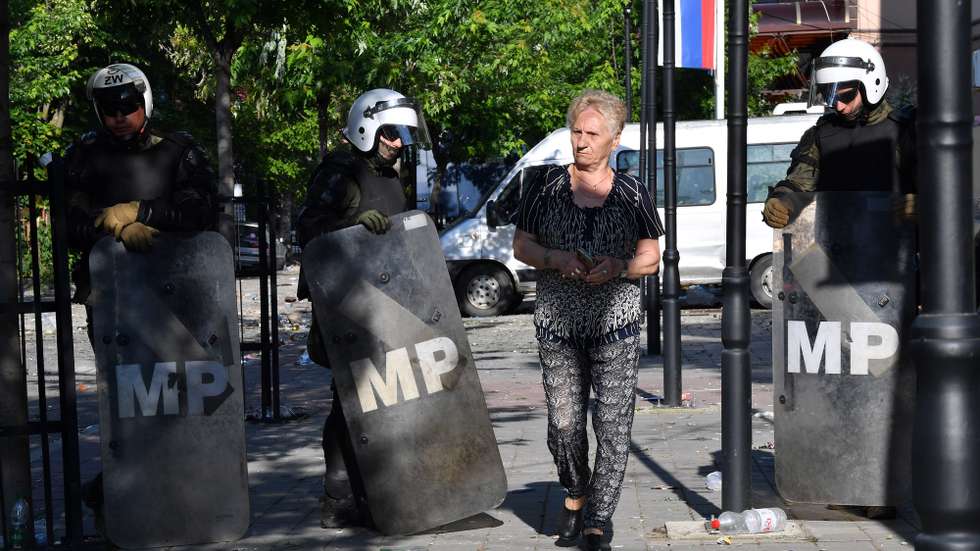epa10662724 A woman walks past soldiers of NATO-led international peacekeeping Kosovo Force (KFOR) as they set up positions in front of the building of the municipality in Zvecan, Kosovo, 30 May 2023. At least 25 KFOR peacekeepers and 53 civilians were injured after clashes between security forces and ethnic Serbs broke out in Zvecan on 30 May 2023. Tensions continue in northern Kosovo’s region, with a majority of ethnic Serbian people, which arose after ethnic Albanians mayors took offices in four towns following elections boycotted by the Serbian community.  EPA/GEORGI LICOVSKI