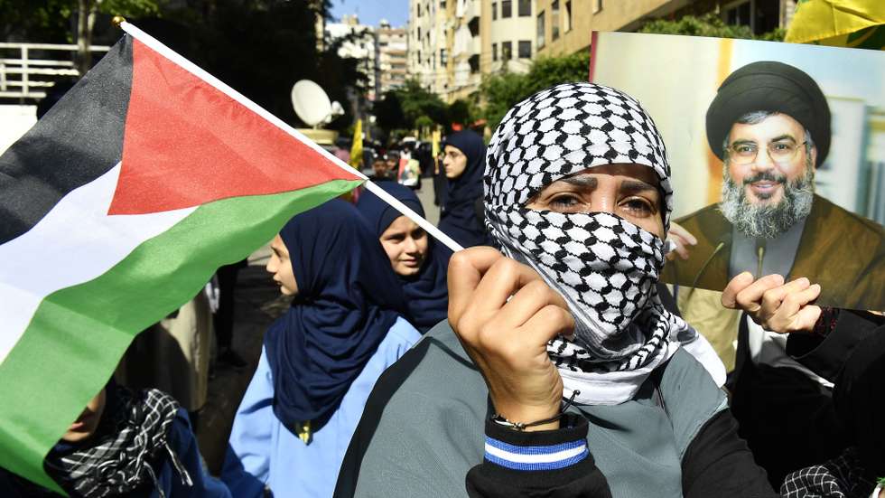 epa10925679 A protester holds a Palestinian flag next to a photo of Hezbollah leader Hassan Nasralla during a protest organized by Hezbollah in solidarity with the Palestinian people, following a strike on a hospital in the Gaza Strip, in the southern suburbs of Beirut, Lebanon, 18 October 2023. According to Palestinian authorities in Gaza hundreds of people have been killed in the explosion at a Gaza hospital on 17 October. Israel has denied responsibility and said a Palestinian Islamic Jihad (PIJ) rocket misfire caused the blast.  EPA/ABBAS SALMAN