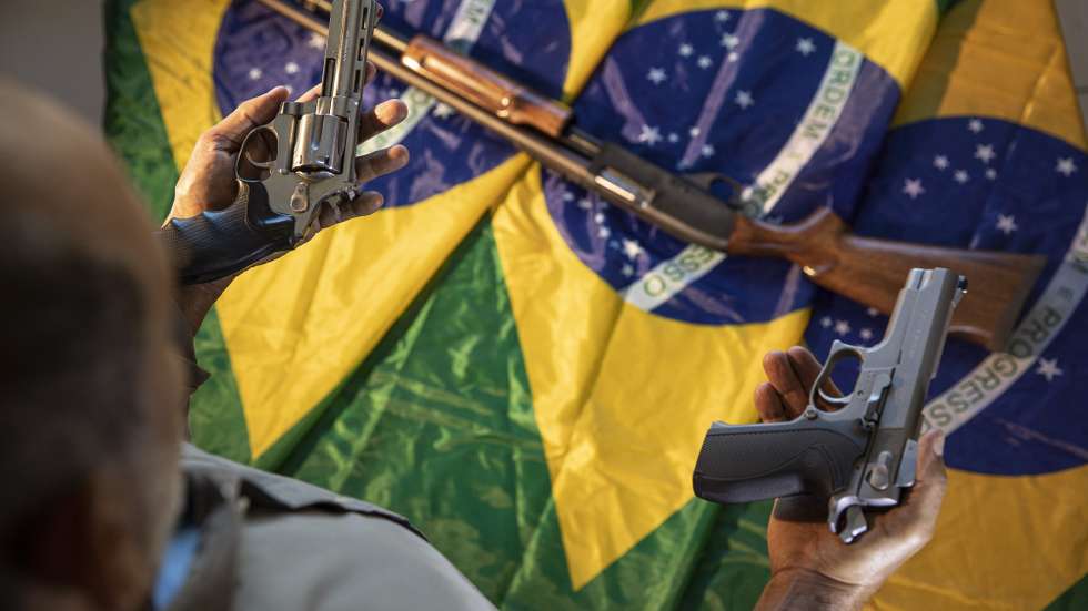 epa10161714 A 65-year-old man poses with three firearms that he uses for his personal security, and Brazilian flags in Brasilia, Brazil, 25 August 2022 (issued 05 September 2022). The number of armed civilians in Brazil has increased by 473% since the far-right Jair Bolsonaro came to power in January 2019, and the matter worries the electoral authorities ahead of the 02 October presidential elections.  EPA/Joedson Alves