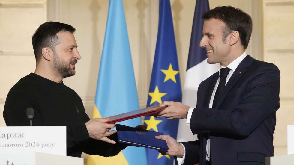 epa11159268 French President Emmanuel Macron (R) and his Ukrainian counterpart Volodymyr Zelensky exchange documents after signing an agreement at the Elysee Palace in Paris, France, 16 February 2024. French President Emmanuel Macron will sign a bilateral security agreement with his Ukrainian counterpart, Volodymyr Zelensky to provide 'long-term support' to the war-ravaged country which has been battling Russia's full-scale invasion for nearly two years.  EPA/THIBAULT CAMUS / POOL MAXPPP OUT