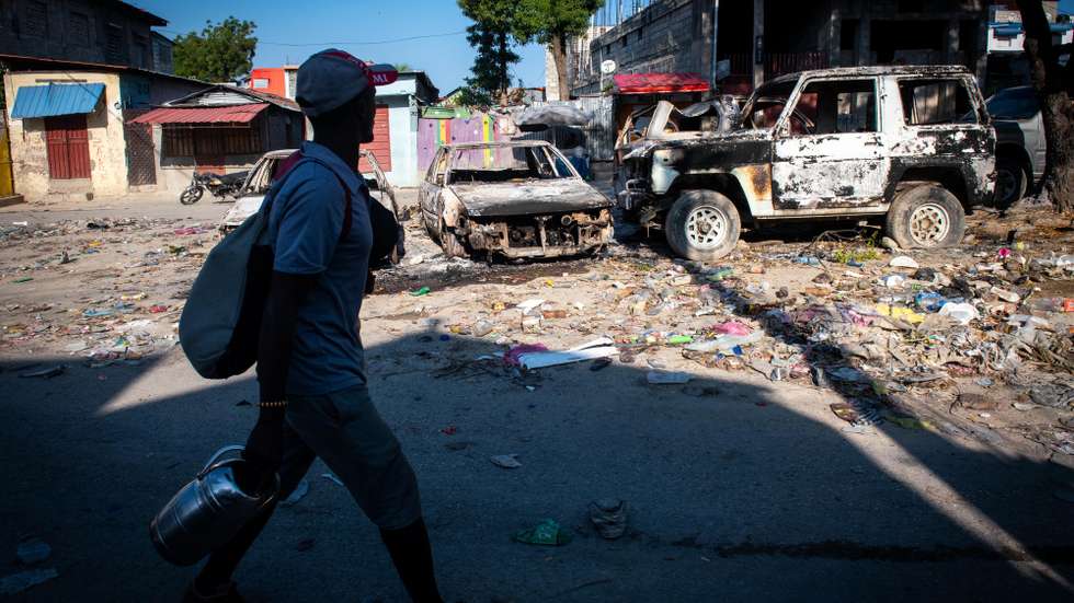 epa11209907 A man walks in front of burned vehicles due to violence in Port-au-Prince, Haiti, 09 March 2024. Suspected criminals were killed by the Haitian National Police during an attack on the National Palace on 08 March orchestrated by the 'Vivre Ensemble' coalition of armed gangs, according to local media published on 09 March.  EPA/JOHNSON SABIN