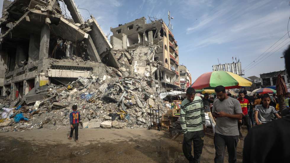 epa11260666 Palestinians walk past kiosks set up next to destroyed buildings on the last Friday of Ramadan along a street in Al Nusairat refugee camp, Gaza Strip, 05 April 2024. More than 33,000 Palestinians and over 1,450 Israelis have been killed, according to the Palestinian Health Ministry and the Israel Defense Forces (IDF), since Hamas militants launched an attack against Israel from the Gaza Strip on 07 October 2023, and the Israeli operations in Gaza and the West Bank which followed it. Up to 1.9 million people have been displaced throughout the Gaza Strip.  EPA/MOHAMMED SABER