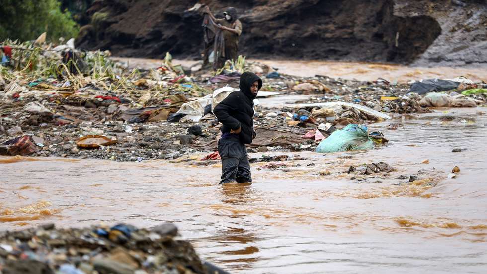 epa11304389 A man (C) crosses a river close to where a body of a man was discovered as the flooded Gitathuru River receeded three days after heavy rainfall broke its banks damaging the surrounding neighborhoods, in Mathare, Nairobi, Kenya, 27 April 2024. According to the Kenya Red Cross Society, the flooding left at least 75 dead as more bodies continue to be discovered, and more than 100,000 people have been affected by the March-May rains that continue to rise, including over 40,000 people displaced. Kenya's meteorological department predicts more heavy rainfall as floods continue to destroy properties in various parts of the country.  EPA/Daniel Irungu  ATTENTION: GRAPHIC CONTENT