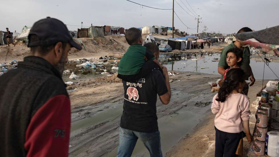epa11303580 Palestinians walk near tents for internally displaced people next to a sewage spill at a temporary camp in Rafah camp, southern Gaza Strip, 26 April 2024. Since 07 October 2023, up to 1.7 million people, or more than 75 percent of the population, have been displaced throughout the Gaza Strip, some more than once, in search of safety, according to the United Nations Relief and Works Agency for Palestine Refugees in the Near East (UNRWA), which added that the Palestinian enclave is 'on the brink of famine', with 1.1 million people (half of its population) 'experiencing catastrophic food insecurity' due to the conflict and restrictions on humanitarian access.  EPA/HAITHAM IMAD