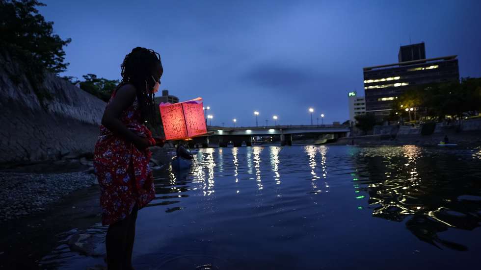 epa08587259 Seven-year-old Kenyan girl Joyce Makokha stands in the water as she placs a lantern on the water of Motoyasu River near the Peace Memorial Park in Hiroshima, western Japan, 06 August 2020. Only a handful of representatives released lanterns on the water after the annual floating lantern event which attracts thousands of people has been canceled this year to avoid the spreading of the coronavirus disease (COVID-19) pandemic. On 06 August 2020 Japan marks the 75th anniversary of the bombing of Hiroshima. In 1945 the United States dropped two nuclear bombs over the cities of Hiroshima and Nagasaki on 06 and 09 August respectively, killing more than 200,000 people. This year's commemoration events were either canceled or scaled down amid the ongoing coronavirus pandemic.  EPA/DAI KUROKAWA