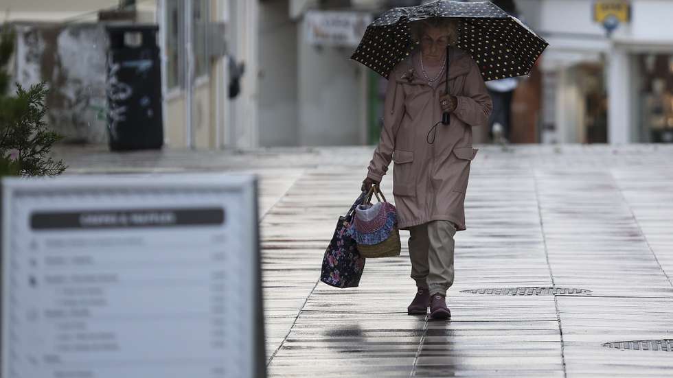 Mulher com chapéu de chuva na Costa de Caparica, Almada, 4 de novembro de 2024. CARLOS M. ALMEIDA/LUSA