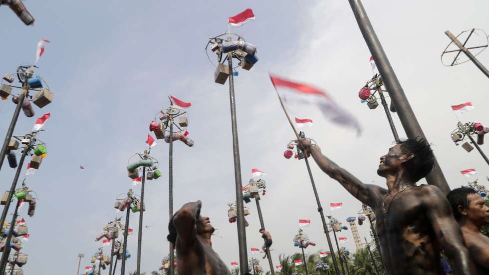 epaselect epa11552479 A participant waves the Indonesia's national flag after a greased pole-race locally known as 'Panjat Pinang' to mark the 79th anniversary of Indonesia's independence day at Ancol Beach in Jakarta, Indonesia, 17 August 2024. Indonesia celebrated its Independence Day with ceremonies held for the first time at Garuda Palace in the new capital of Nusantara in East Kalimantan, as well as at the Presidential Palace in Jakarta, celebrating the 79th anniversary of its independence from the Netherlands on 17 August 1945.  EPA/BAGUS INDAHONO