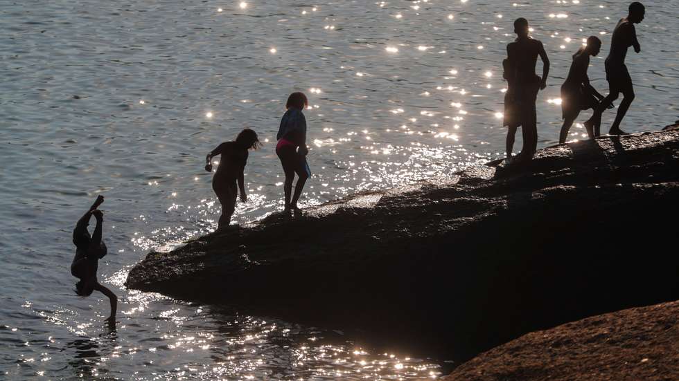epa08533434 Bathers at the Arpoador beach in Rio de Janeiro, Brazil, 07 July 2020. The temperature registered 28 degrees in the middle of winter.  EPA/Antonio Lacerda