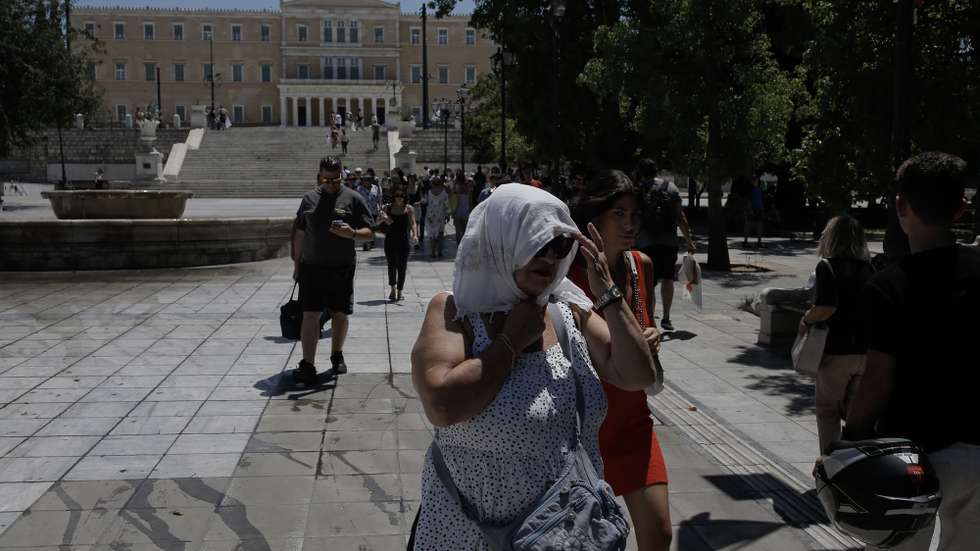 epa11487454 A pedestrian wearing a headscarf to shield from the sun, walks through Syntagma square during a heatwave at the monument of the unknown soldier in front of the parliament building in Athens, Greece, 19 July 2024. The high temperatures, locally above 40 degrees Celsius, will continue in Greece until 22 July. From 23 July, there will be a gradual drop in temperature, both in terms of maximum and minimum values, which will be felt by the middle of next week in most areas.  EPA/KOSTAS TSIRONIS