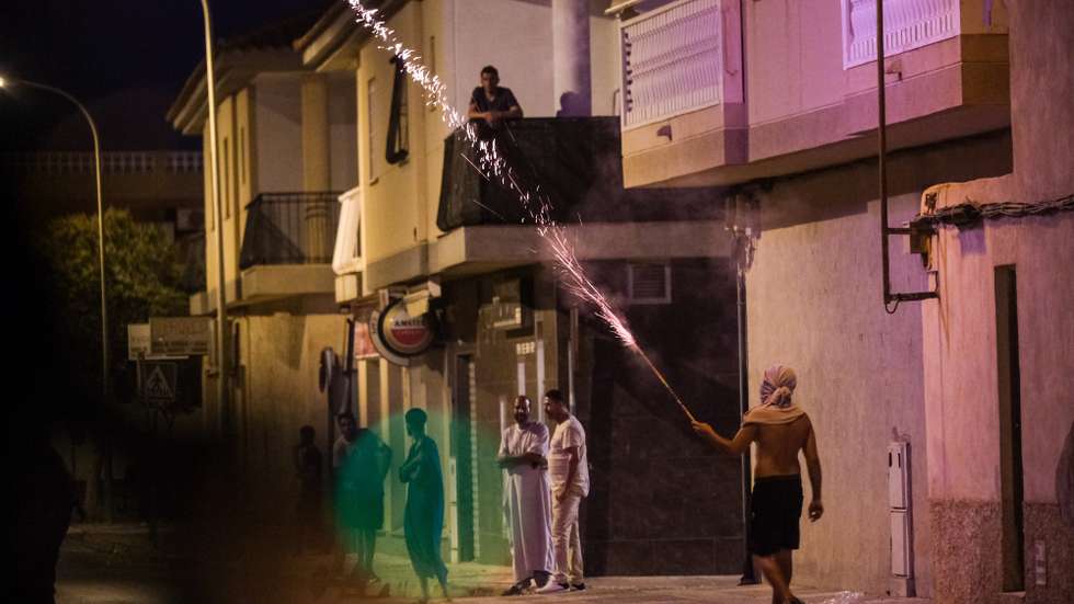 epa12238587 Residents look at a masked man at the San Antonio district in the town of Torre Pacheco, Murcia, southeastern Spain, late 14 July 2025. Anti-migrant unrest in Torre Pacheco, which left several people injured and resulted in multiple arrests, was sparked by an assault on a 68-year-old resident, allegedly by migrants, according to authorities. The incident led to three days of violence in the town, which has a population of approximately 40,000 and a large Maghrebi immigrant community.  EPA/PABLO MIRANZO