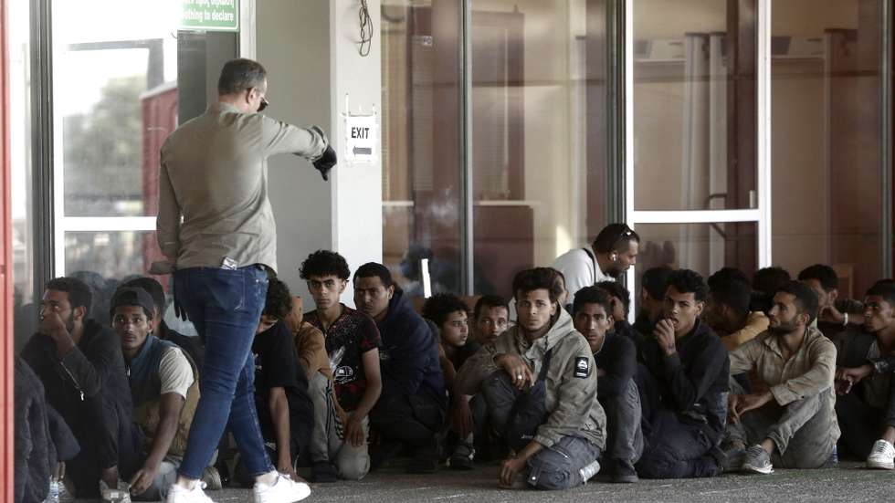 epa12228654 Refugees and migrants sit outside the Greek Port authority after being transported by small launch boats from a bulk carrier, at the port of Lavrio, Greece, 10 July 2025. Over 500 refugees and migrants rescued in Crete were transported overnight by a cargo ship to the port of Lavrio.  EPA/YANNIS KOLESIDIS