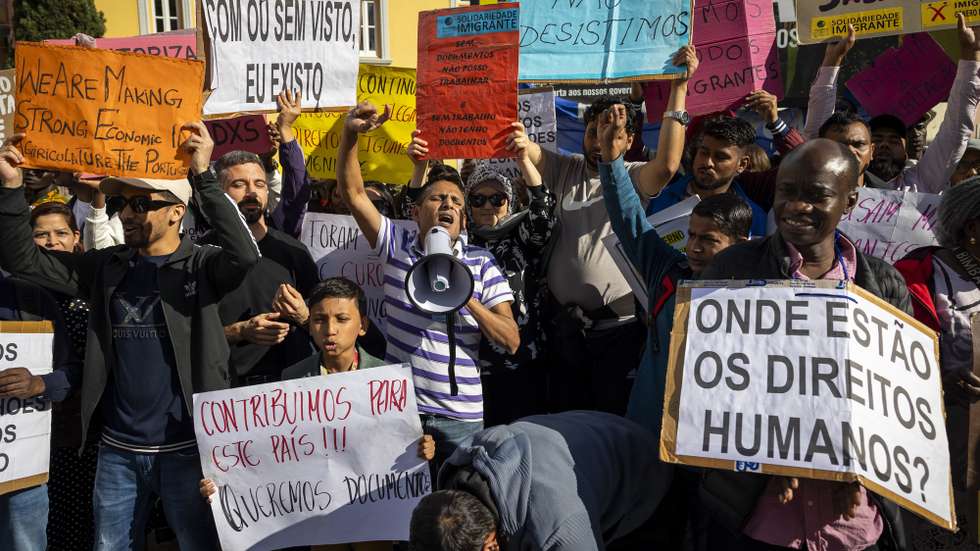 Membros de associações de imigrantes gritam palavras de ordem durante uma manifestação para reivindicar a reposição de artigos que permitiam aos imigrantes avançar com um processo de autorização de residência e ficar legalizados, em frente à Assembleia da República, em Lisboa, 25 de outubro de 2024. JOSÉ SENA GOULÃO/LUSA