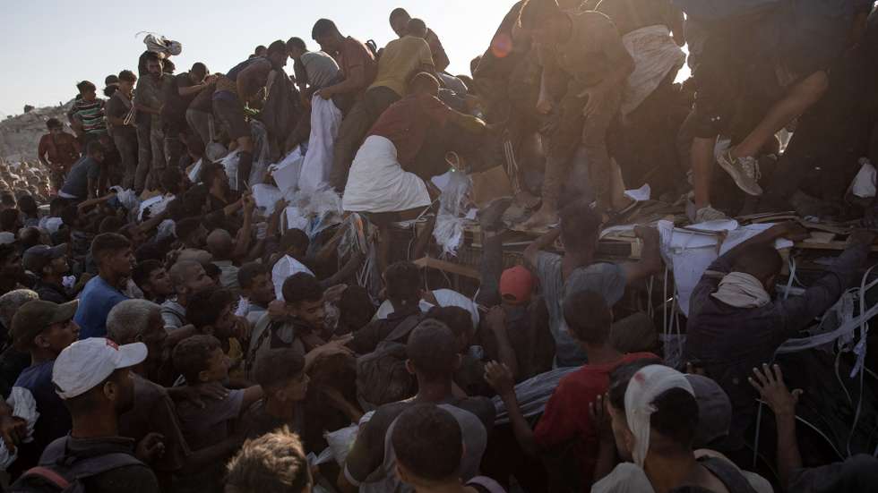 epa12283324 Internally displaced Palestinians climb aid trucks to get food near a food distribution point in the Morag corridor, south of Khan Younis, in the southern Gaza Strip, 04 August 2025.  EPA/HAITHAM IMAD