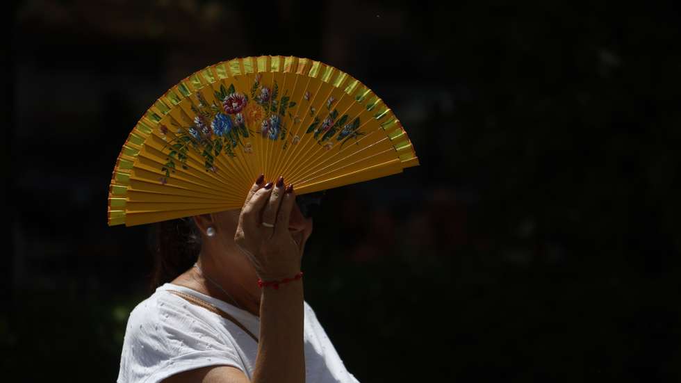 epa12226732 A woman covers her head with a folding fan in Cordoba, southern Spain, 09 July 2025. A yellow alert was issued for high temperatures, with the temperature expected to reach up to 40 degrees Celsius in the city during the day.  EPA/SALAS