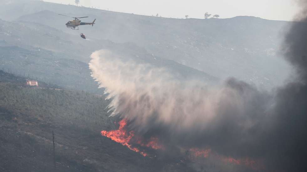 Um helicópetro combate as chamas durante o incêndio na encosta da aldeia de Moura da Serra, Arganil, 14 de agosto de 2025. De acordo com os dados disponíveis no ‘site’ da Autoridade Nacional de Emergência e Proteção Civil (ANEPC), quase 900 operacionais combatiam o fogo que deflagrou na quarta-feira na freguesia de Piódão, no concelho de Arganil, distrito de Coimbra, e se estendeu depois aos municípios de Oliveira do Hospital e Pampilhosa da Serra (Coimbra), e de Seia, já no distrito da Guarda. PAULO CUNHA/LUSA