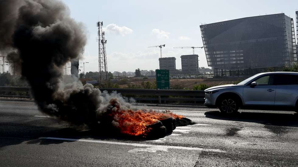 epa12323025 A burning tire set on fire by protesters on the road No. 4 connecting Jerusalem and the airport to Haifa, Israel, 26 August 2025, part of the activities of the hostages' families on the  national day of struggle - "Israel Stands Together"  EPA/ATEF SAFADI