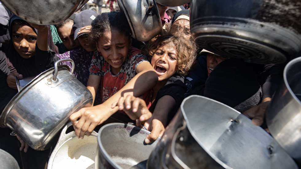 epaselect epa12317917 Palestinians queue to receive a meal from a kitchen that provides free food for displaced people in Khan Yunis, southern Gaza Strip, on 23 August, 2025.  EPA/HAITHAM IMAD