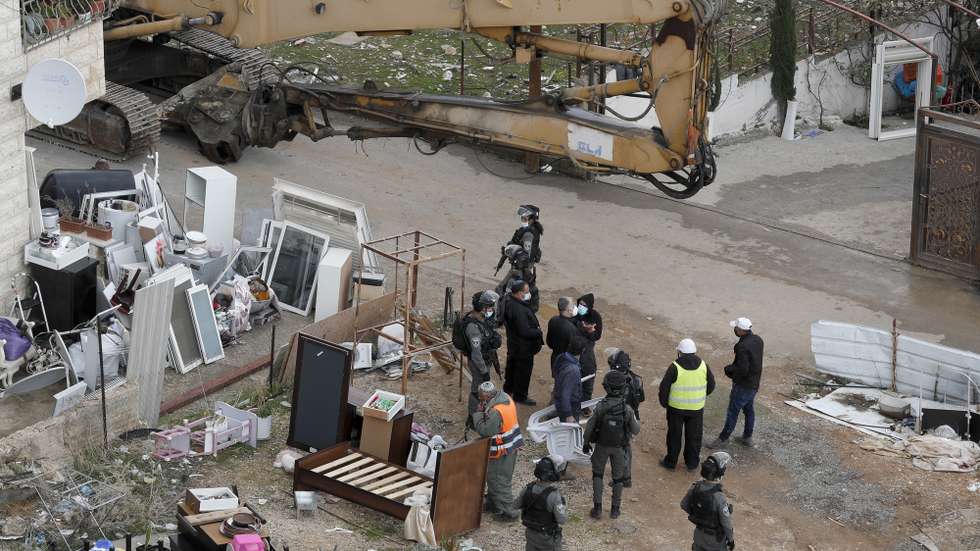 epa09708348 Israeli soldiers stand guard as machinery demolish a Palestinian house belonging to Karameh family, in al-Tur neighborhood of East Jerusalem, 25 January 2022. The Israeli municipality of West Jerusalem demolished the two-story building belonging to the Karameh family after it was evacuated claiming it was constructed without a permit. Activists say hundreds of Palestinian homes could be evacuated and demolished as Israeli authorities claim they are constructed without needed permits which are usually impossible to obtain by Palestinians.  EPA/ATEF SAFADI