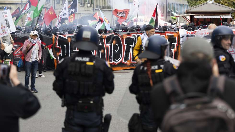 epa12446877 Policemen stand guard as people hold banners and wave Palestinian flags during an unauthorized rally in solidarity with the Palestinian people, in Bern, Switzerland, 11 October 2025.  EPA/PETER KLAUNZER