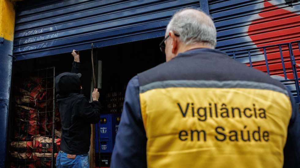 epa12426378 A health inspector closes a liquor store during an operation at a warehouse in the southern part of Sao Paulo, Brazil, 02 October 2025. Brazilian authorities have stepped up police action against the distribution of adulterated beverages after the number of possible deaths rose to eight and cases of methanol poisoning, a highly toxic biofuel, rose to 59.  EPA/Isaac Fontana