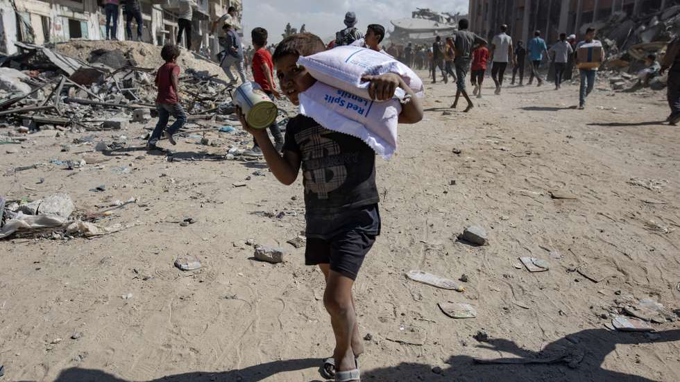 epa12448496 Palestinians take aid supplies from a truck that arrived in Khan Yunis in the southern Gaza Strip, 12 October 2025.  EPA/HAITHAM IMAD