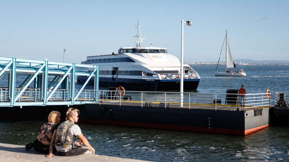 Um casal de turistas observa a chegada de um navio de passageiros, no Terreiro do Paço, em Lisboa, 10 de outubro de 2024. Cacilheiro. Catamarã. Transportes. Navio. Rio Tejo. Turismo. ANTÓNIO PEDRO SANTOS/LUSA