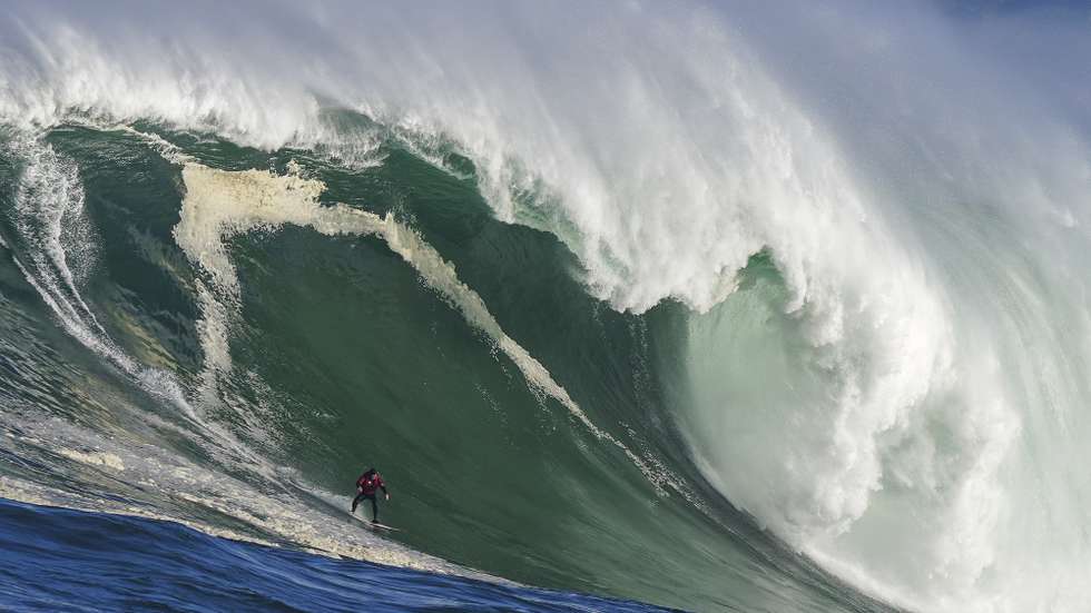 epa09694904 Surfer Jake Kolnik rides a wave at Sunset offshore reef in the Atlantic Ocean outside Cape Town, South Africa, 19 January 2022. Big swells are unusual during the southern hemisphere summer but a storm in the South Atlantic generated powerful swells that broke on the Cape's outer reefs making good conditions for the sport. This is the first big swell of the year. The waves were too big to paddle into so surfers used wave runners to tow each other into the waves.  EPA/NIC BOTHMA