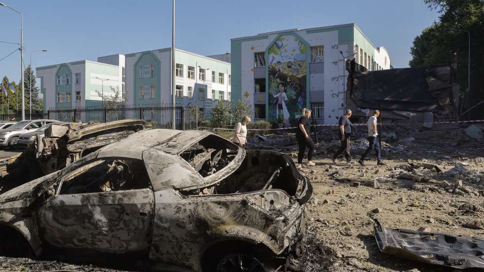epa12214601 Local people walk in a damaged area with destroyed cars near a school building after a Russian airstrike in Kyiv, Ukraine, 04 July 2025, amid the Russian invasion. More than 20 people were injured after Russian forces launched an overnight large-scale combined attack with at least 11 missiles and 539 drones across Ukraine, with Kyiv as the main target, the State Emergency Service (SES) of Ukraine reported.  EPA/SERGEY DOLZHENKO