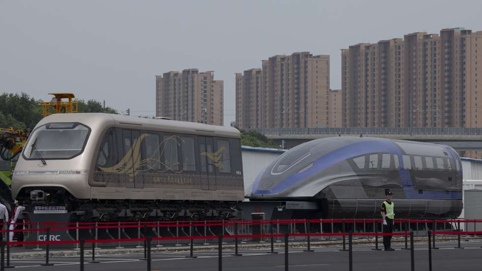 epa12226776 A security guard stands in front of a normal-conducting medium- and low-speed maglev (L) and a normal-conducting high-speed maglev (R) exhibited at the 12th UIC High-Speed Railway Congress at the National Railway Test Center in Beijing, China, 09 July 2025. The congress is held in Beijing from 08 to 11 July 2025.  EPA/ANDRES MARTINEZ CASARES