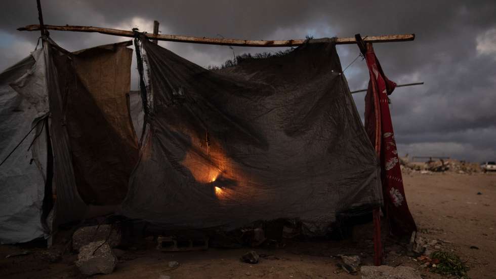 epaselect epa12614566 Members of a displaced Palestinian family warm themselves around a fire outside their shelter in the city of Khan Younis, in the southern Gaza Strip, 27 December, 2025.  EPA/HAITHAM IMAD