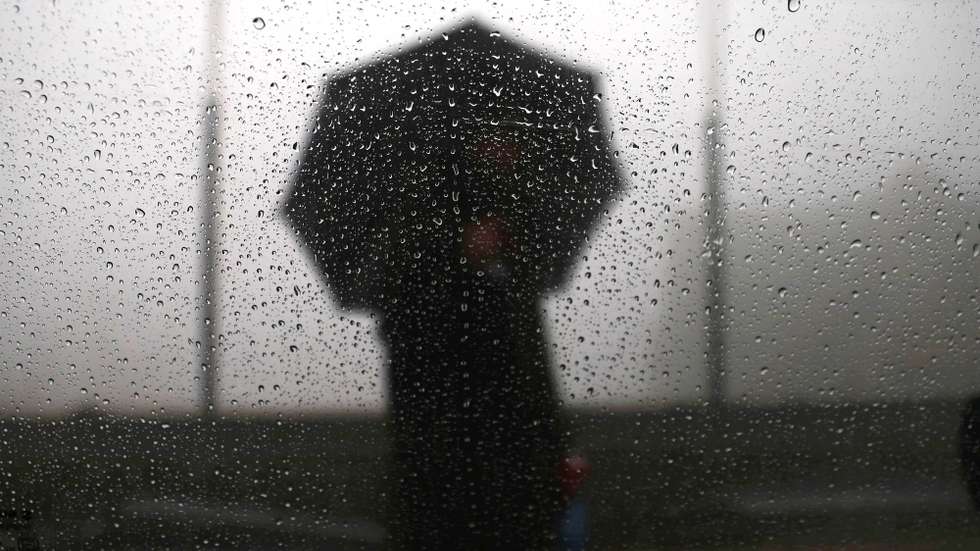 epa12606661 A man holding an umbrella is seen through a car window during rain and fog on the outskirts of Srinagar, the summer capital of Indian Kashmir, 21 December 2025. Kashmir witnessed an end to a prolonged dry spell, with the upper reaches witnessing light to heavy snowfall and the plains witnessing intermittent rains on the day marking the onset of Chillai Kalan, the harshest 40-day winter spell. Meteorological Department officials have forecast ongoing precipitation and colder temperatures as the valley braces for deeper winter conditions.  EPA/FAROOQ KHAN