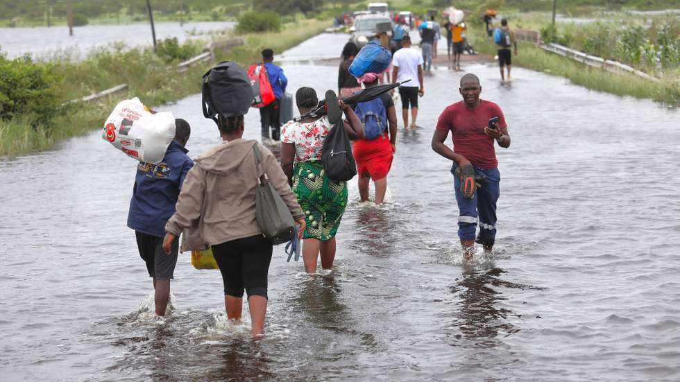 Populares atravessam uma estrada alagada, em Mahocha Homo, Maputo, 20 de janeiro de 2026. No meio de cheias sem memória em Moçambique a moto é o último transporte em Mahocha Homo, a meio caminho entre Manhiça e Palmeiras, onde as águas de um pequeno riacho, que mal alimentava os campos agrícolas, galgaram a estrada. (ACOMPANHA TEXTO DA LUSA DO DIA 24 DE JANEIRO DE 2026). LUÍSA NHANTUMBO/LUSA