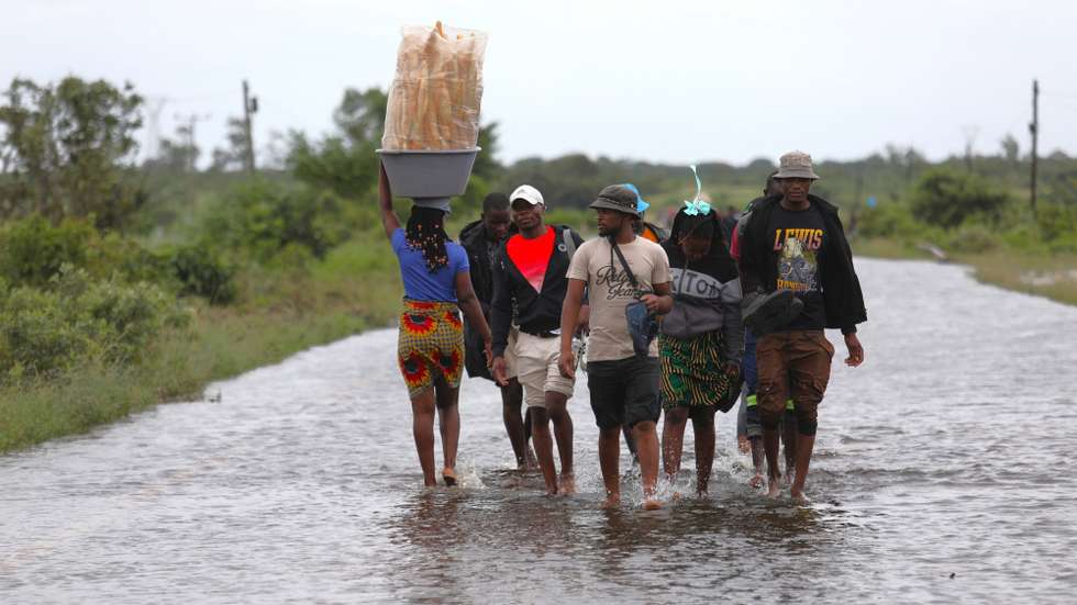 Populares atravessam uma estrada alagada, em Mahocha Homo, Maputo, 20 de janeiro de 2026. No meio de cheias sem memória em Moçambique a moto é o último transporte em Mahocha Homo, a meio caminho entre Manhiça e Palmeiras, onde as águas de um pequeno riacho, que mal alimentava os campos agrícolas, galgaram a estrada. (ACOMPANHA TEXTO DA LUSA DO DIA 24 DE JANEIRO DE 2026). LUÍSA NHANTUMBO/LUSA